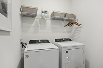 A laundry room with a washer and dryer and a shelf with baskets and a handbag at Arcadia Cartersville Apartments, Georgia, 30121
